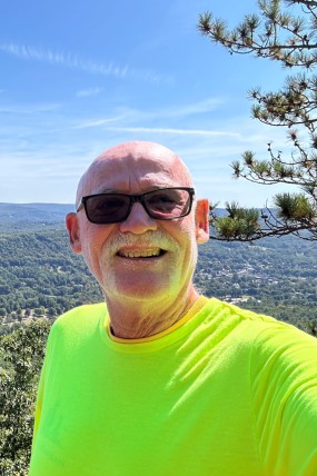 Andy Tolland smiling at camera with scenic view in back
